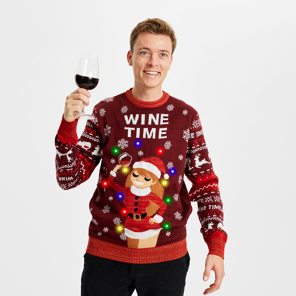 Un homme avec un verre de vin portant un pull rouge de Noël avec la citation